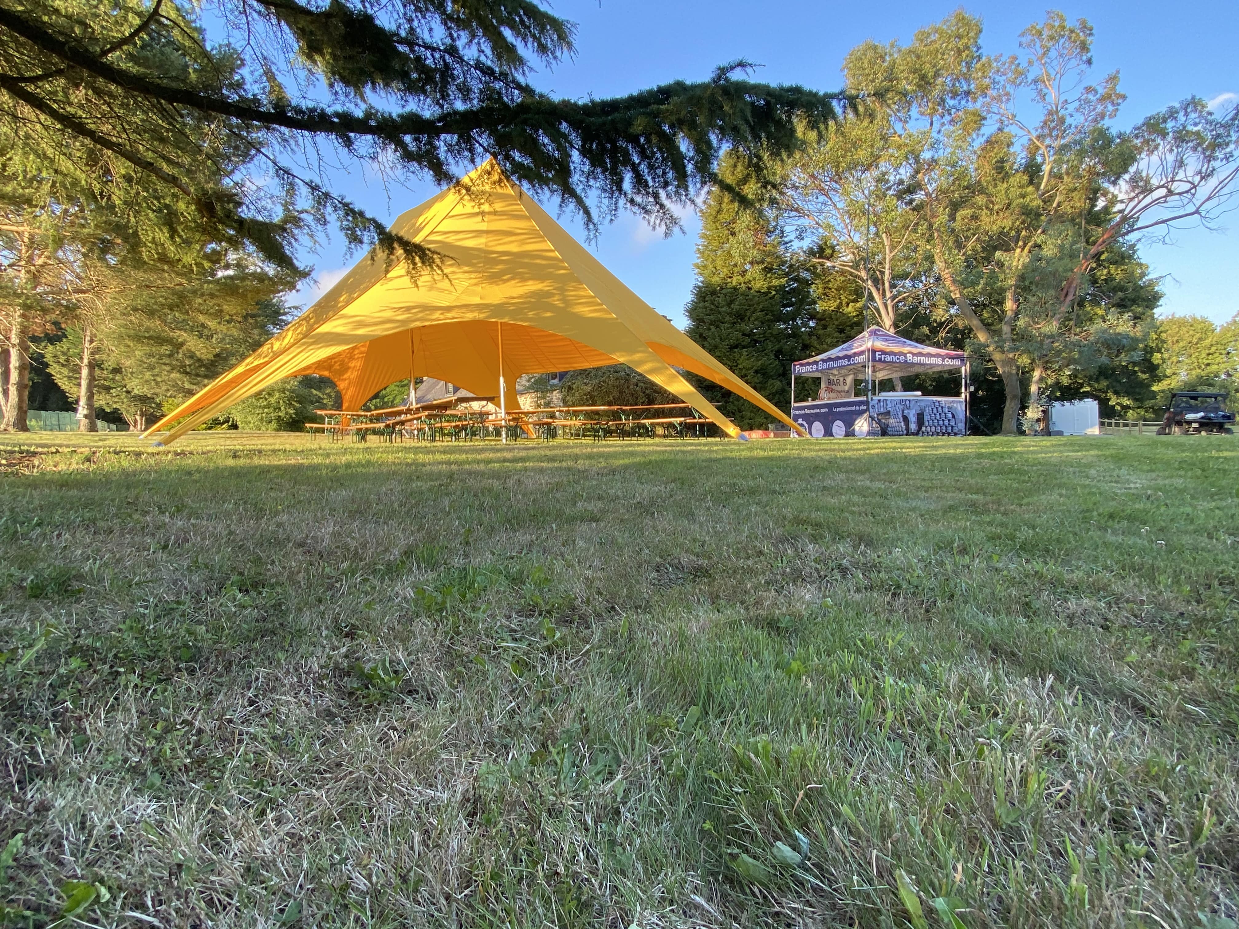 Tente étoile lumineuse et jaune cachée par des arbres